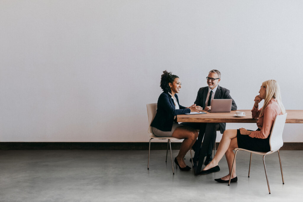 Drei Personen besprechen Zertifizierung und Audit am Tisch – Fokus auf Managementsystemberatung.